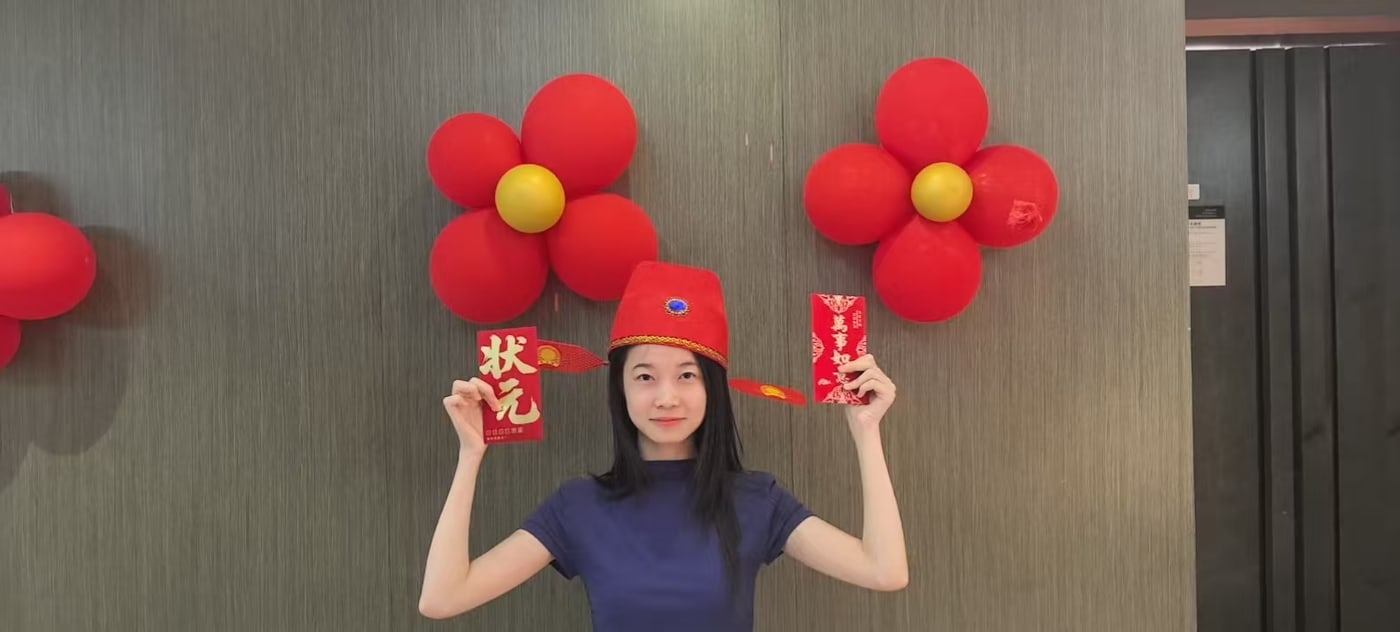 The winner of the bobing round wearing the 状元 top-scholar hat and holding the red packet that comes with it
